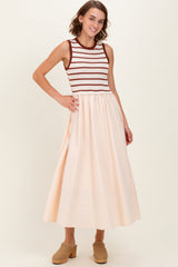 woman wearing a sleeveless striped maxi dress with a fitted bodice and a flowy peach skirt