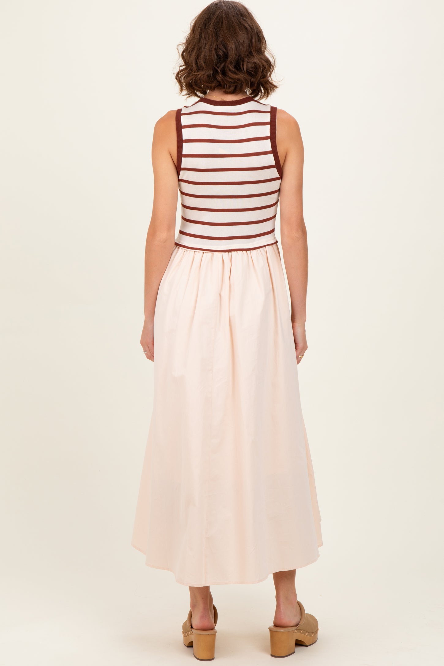 woman wearing a sleeveless striped top with a light pink maxi skirt, seen from the back