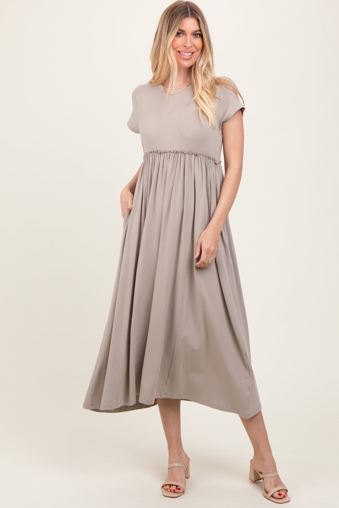 woman wearing a beige short sleeve midi dress with an elastic waist and side pockets