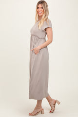 woman wearing a taupe short sleeve maxi dress with a cinched waist and pockets