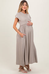 woman wearing a light taupe short sleeve maternity maxi dress with pockets and holding her baby bump