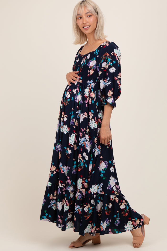 woman wearing a black floral print maternity maxi dress with puff sleeves and a visible baby bump