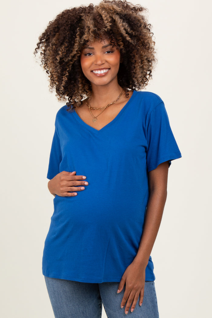 woman wearing a bright blue short sleeve maternity top and holding her baby bump