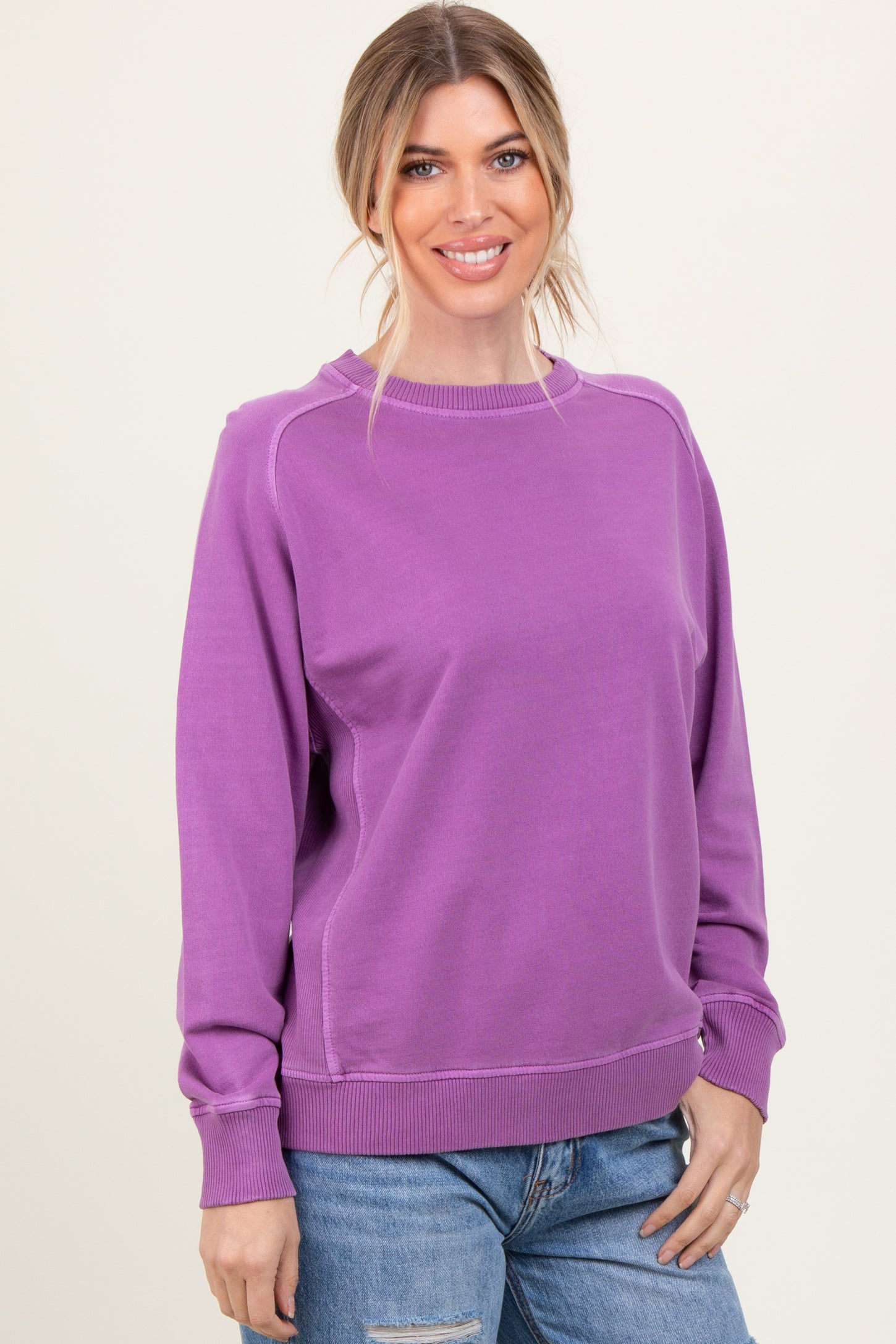 woman wearing a purple long sleeve sweatshirt with a relaxed fit and rounded neckline, smiling at the camera