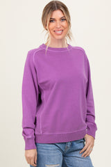 woman wearing a purple long sleeve sweatshirt with a relaxed fit and rounded neckline, smiling at the camera