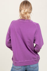 woman wearing a purple long sleeve sweatshirt, viewed from the back, with a relaxed fit and ribbed hem