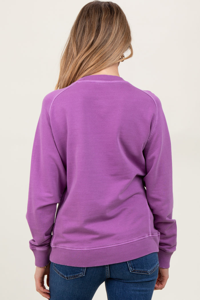 woman wearing a purple maternity sweatshirt, viewed from the back, paired with blue jeans
