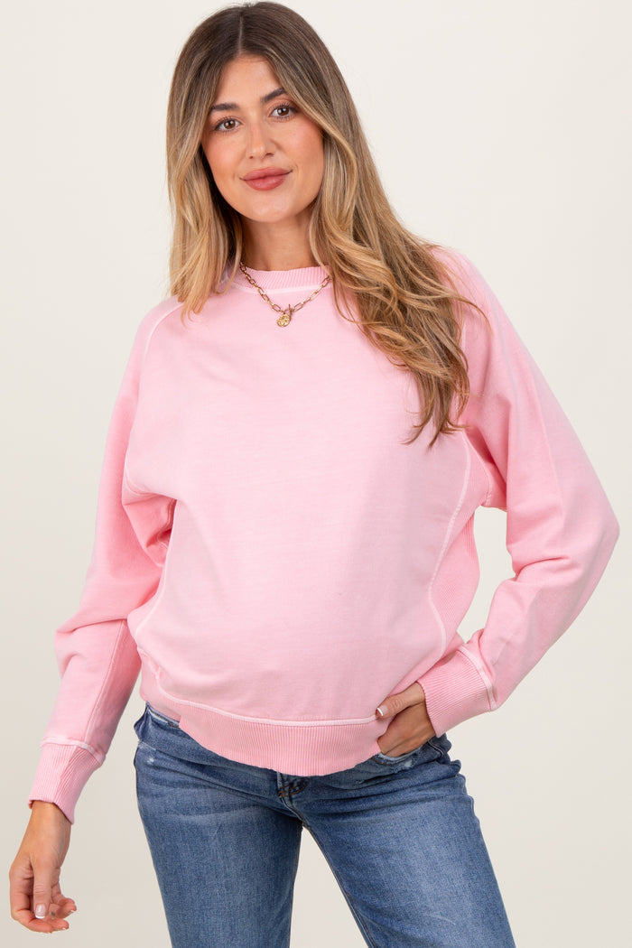 woman wearing a pink long sleeve maternity sweatshirt with a relaxed fit and visible baby bump