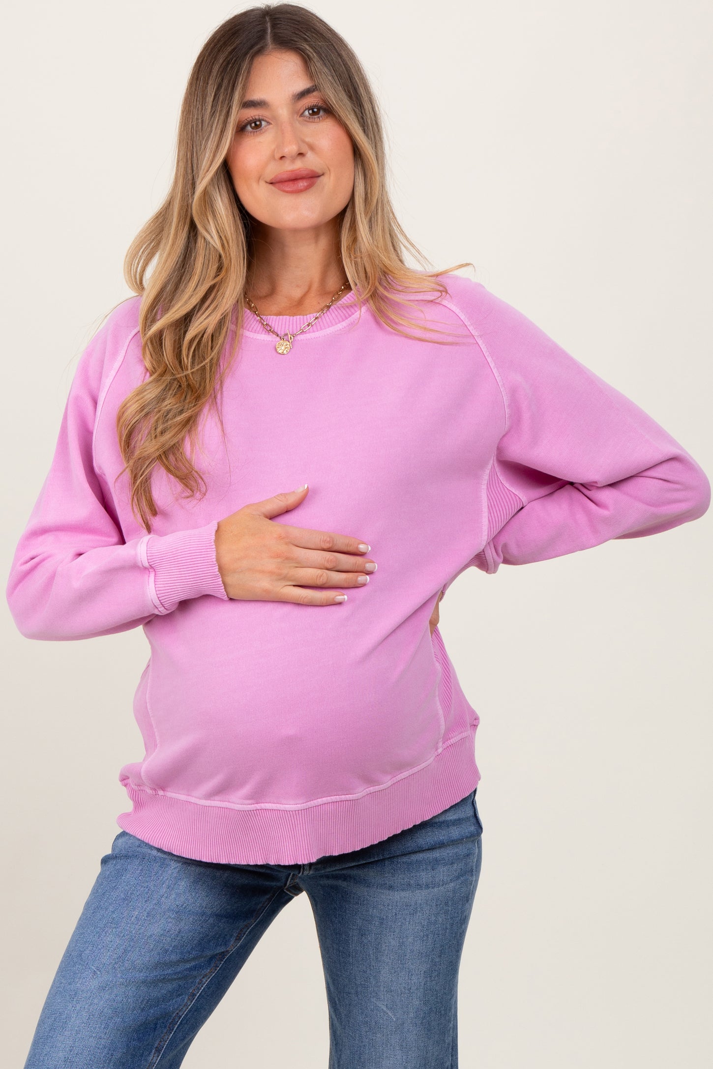 woman wearing a pink maternity sweatshirt and holding her baby bump
