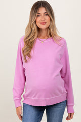 woman wearing a light pink maternity sweatshirt with a relaxed fit and a visible baby bump