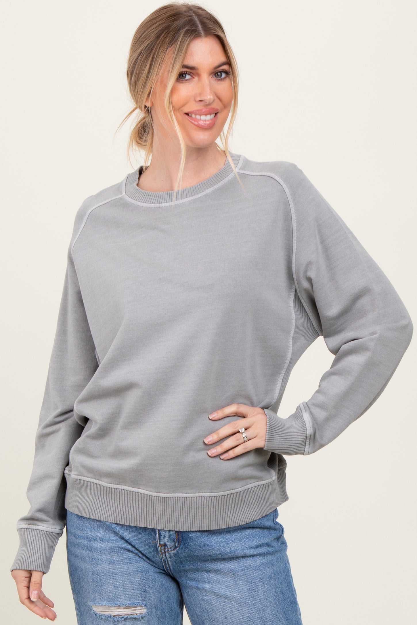 woman wearing a light gray long sleeve sweatshirt with ribbed cuffs and hem