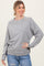 woman wearing a light gray long sleeve sweatshirt with ribbed cuffs and hem