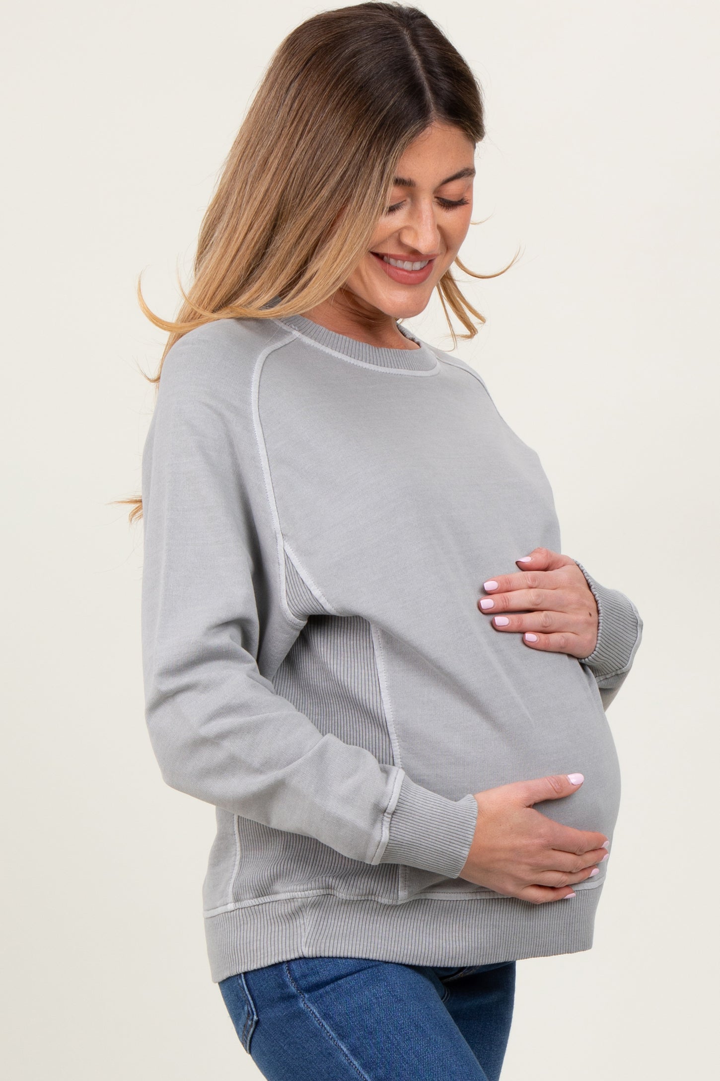 woman wearing a gray maternity sweatshirt and holding her baby bump