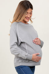 woman wearing a gray maternity sweatshirt and holding her baby bump