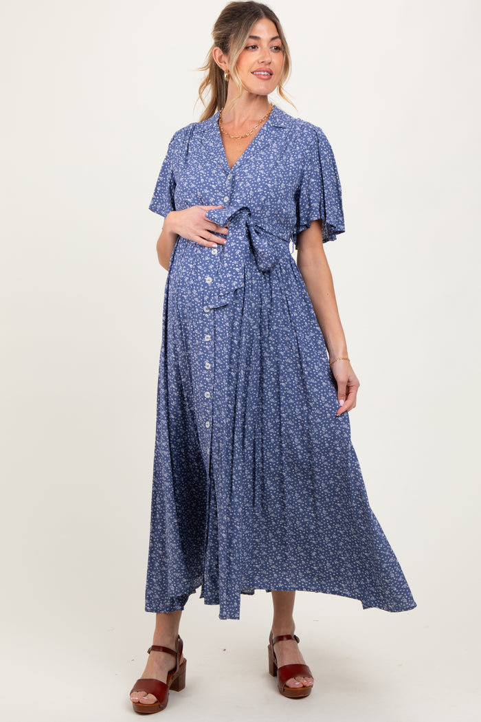 woman wearing a blue floral maternity wrap dress with short sleeves and a tie waist, showing her baby bump