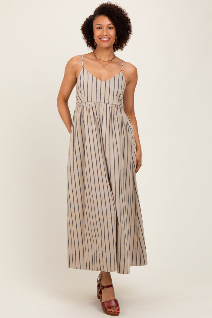 woman wearing a beige striped maxi dress with thin straps and a flared skirt, styled with red heeled sandals
