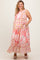 woman wearing a pink patterned maternity plus maxi dress with pockets and ruffled hem, showing her baby bump