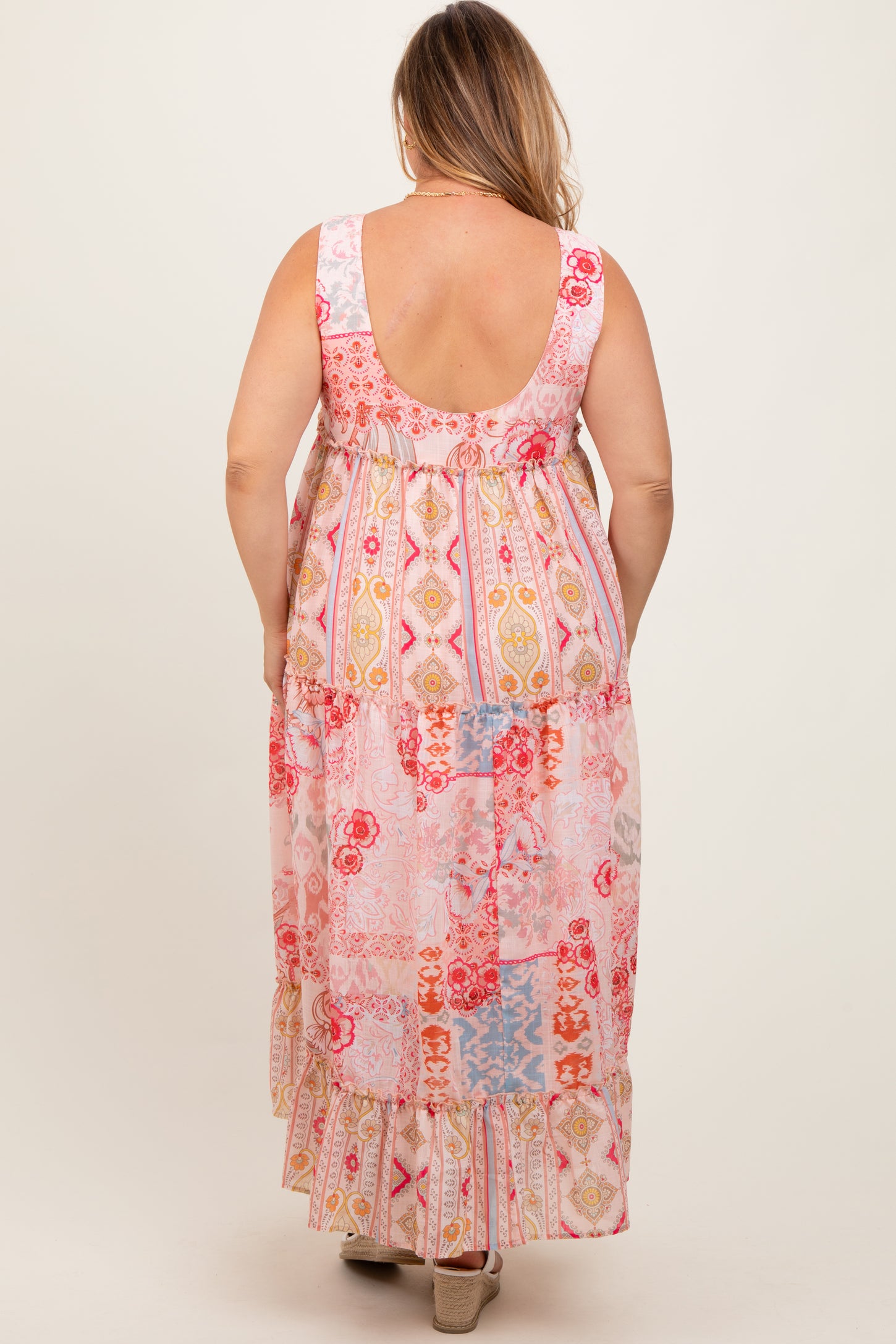 woman wearing a colorful patterned maternity plus maxi dress with a tiered design and a scoop back