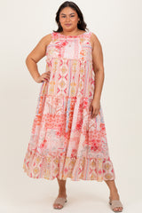 woman wearing a colorful plus size maxi dress with a tiered design and floral patterns, standing with one hand on her hip