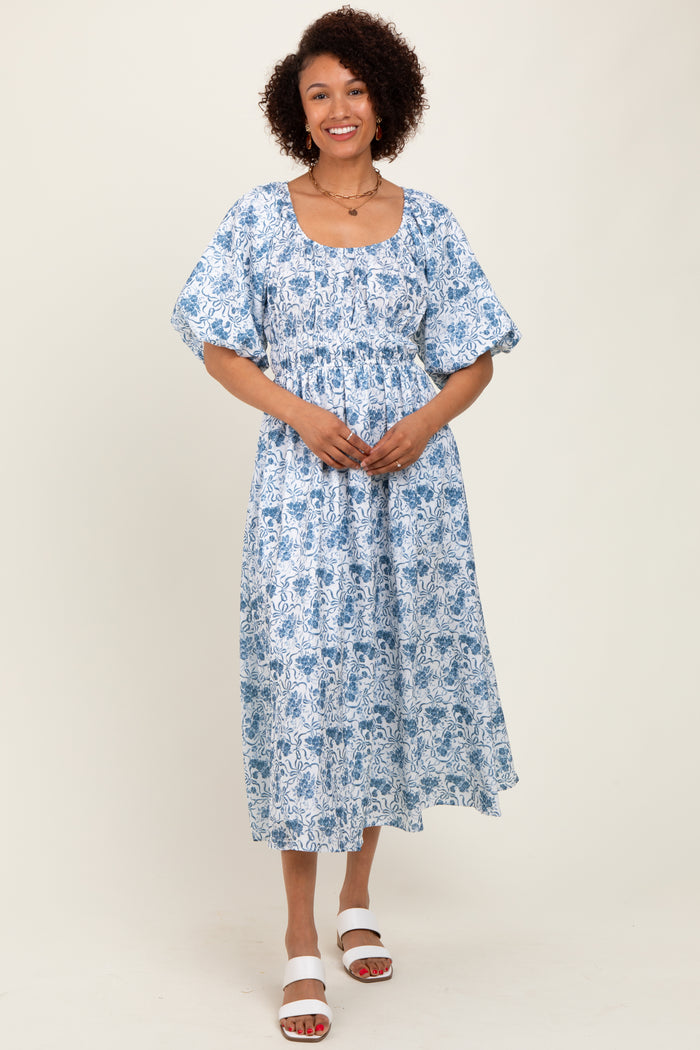 woman wearing a blue and white floral print midi dress with short puff sleeves and a square neckline