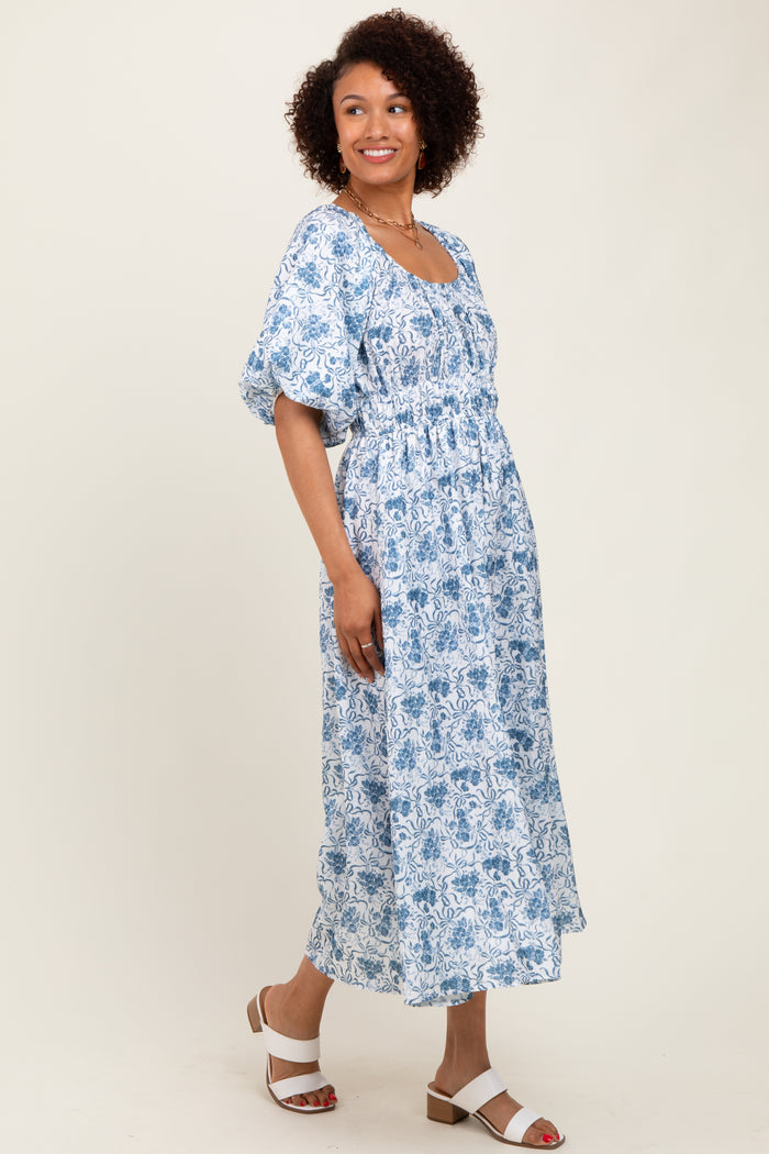 woman wearing a blue and white floral maxi dress with short puff sleeves and a cinched waist