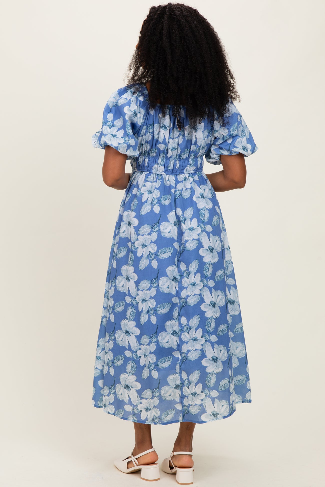 woman wearing a blue floral maxi dress with puff sleeves, showing the back view