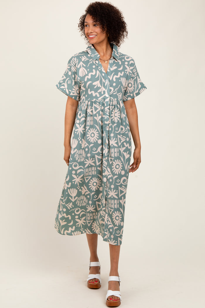 woman wearing a teal floral print midi shirt dress with short sleeves and a tie waist, standing on a neutral background