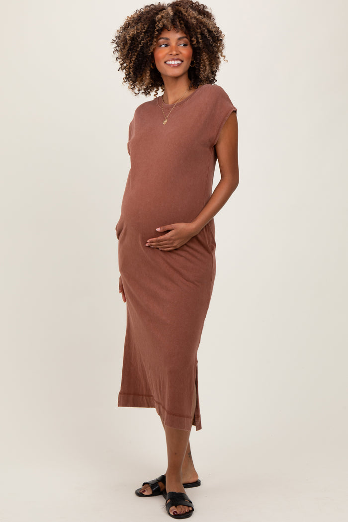 woman wearing a brown sleeveless maternity dress with side pockets and a visible baby bump