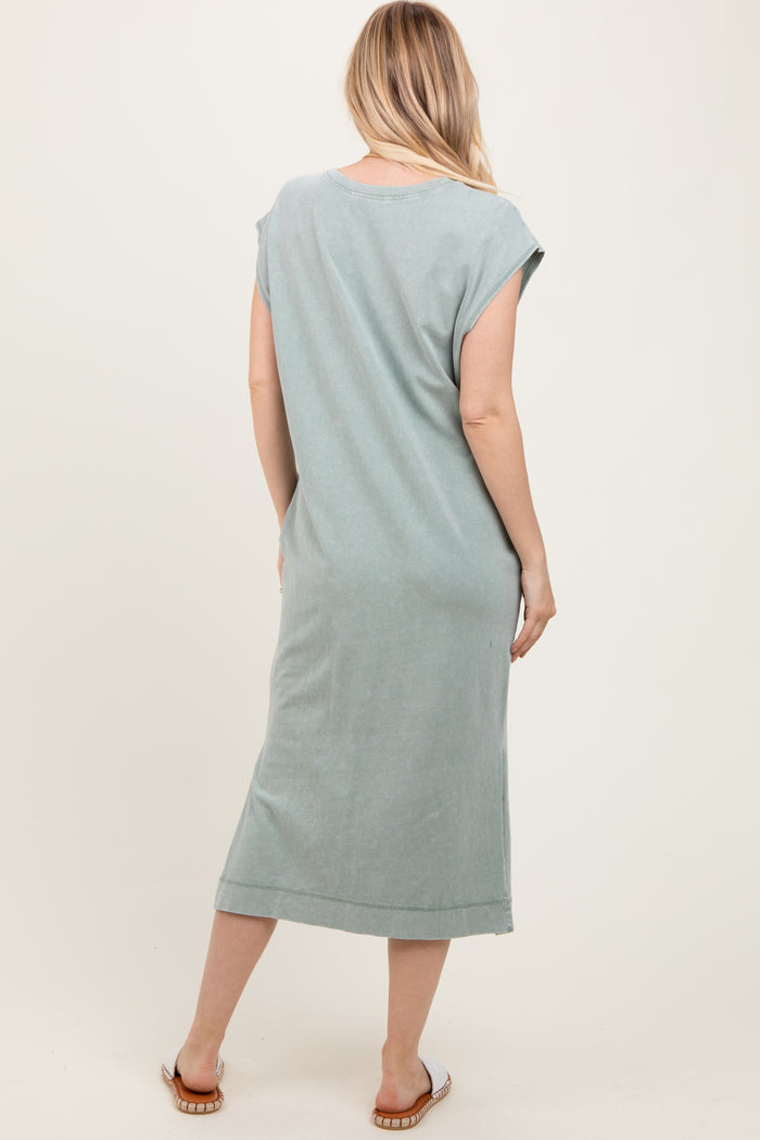 woman wearing a sage green short sleeve midi dress, showing the back view, with a relaxed fit and side slits