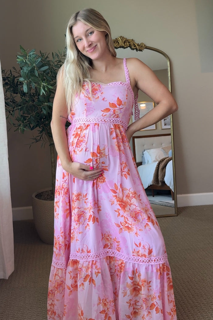 woman wearing a pink floral maternity maxi dress and holding her baby bump