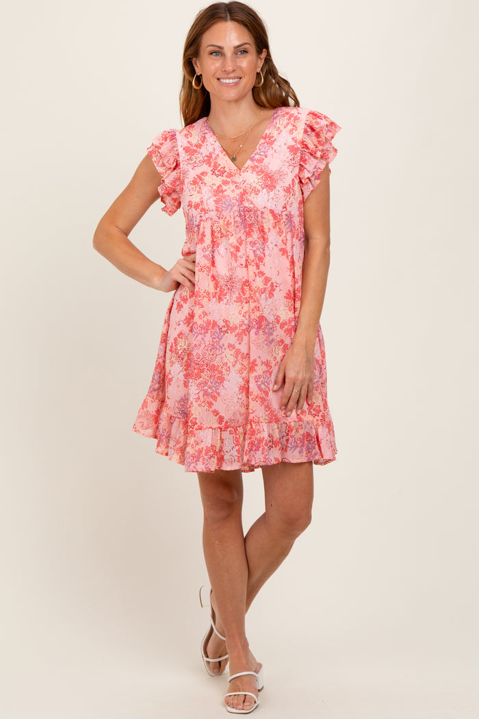 woman wearing a pink floral mini dress with ruffle sleeves and a tiered skirt, standing and smiling