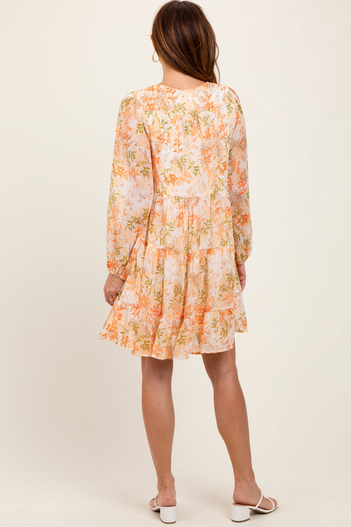 woman wearing a floral long sleeve mini dress in pastel colors with a tiered skirt and a relaxed fit