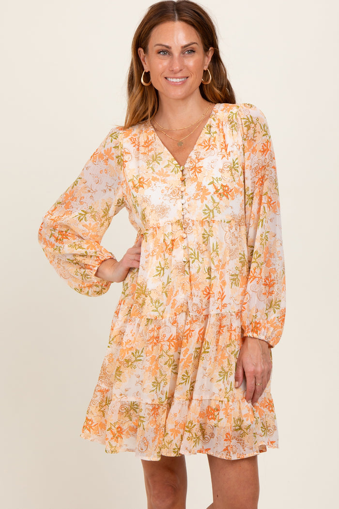 woman wearing a floral print orange and white long sleeve dress with a v-neck and tiered skirt