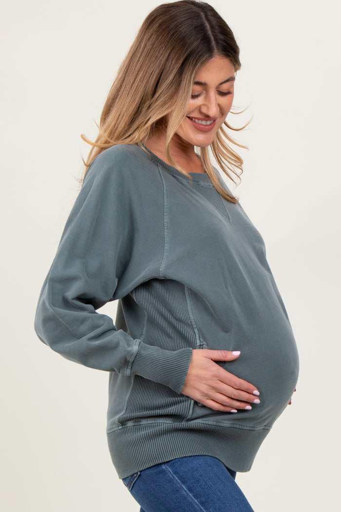 woman wearing a dusty green maternity sweatshirt and holding her baby bump