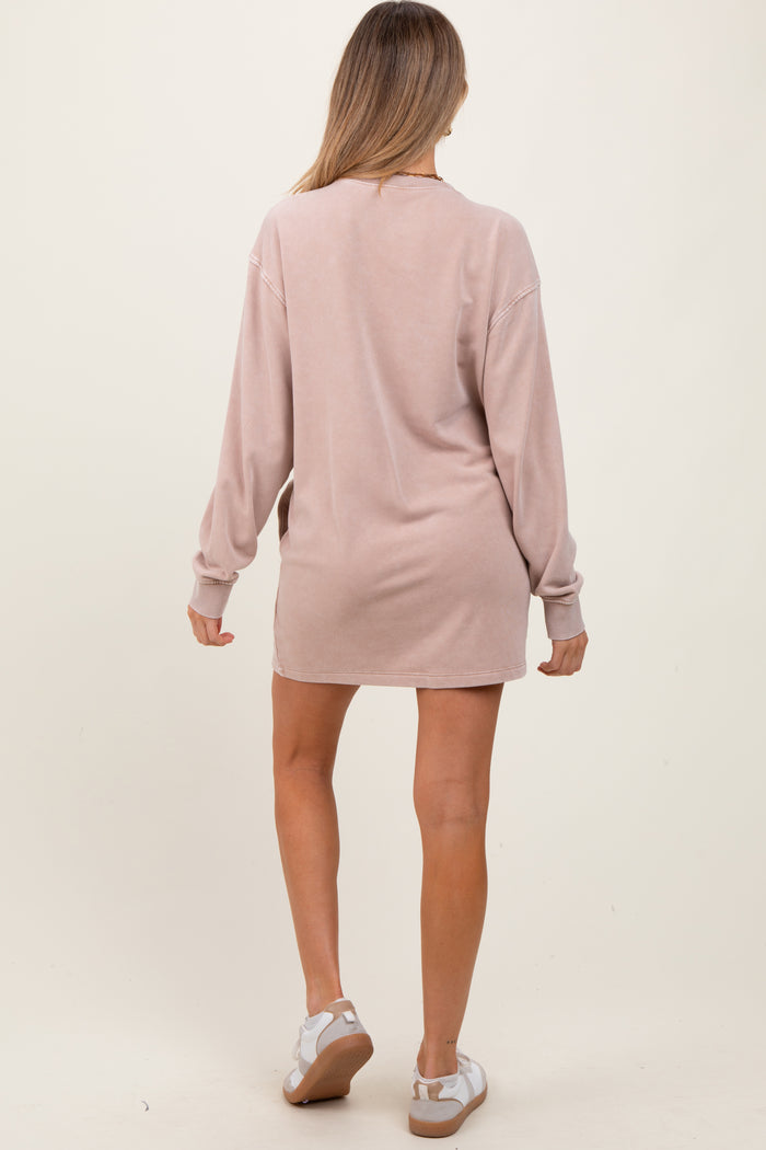 woman wearing a light pink maternity dress with long sleeves, standing with her back to the camera