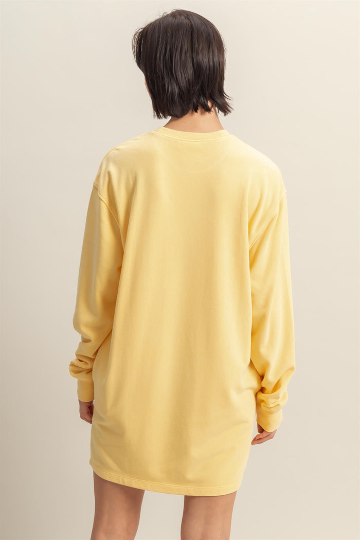 woman wearing a yellow oversized long sleeve t-shirt dress, viewed from the back
