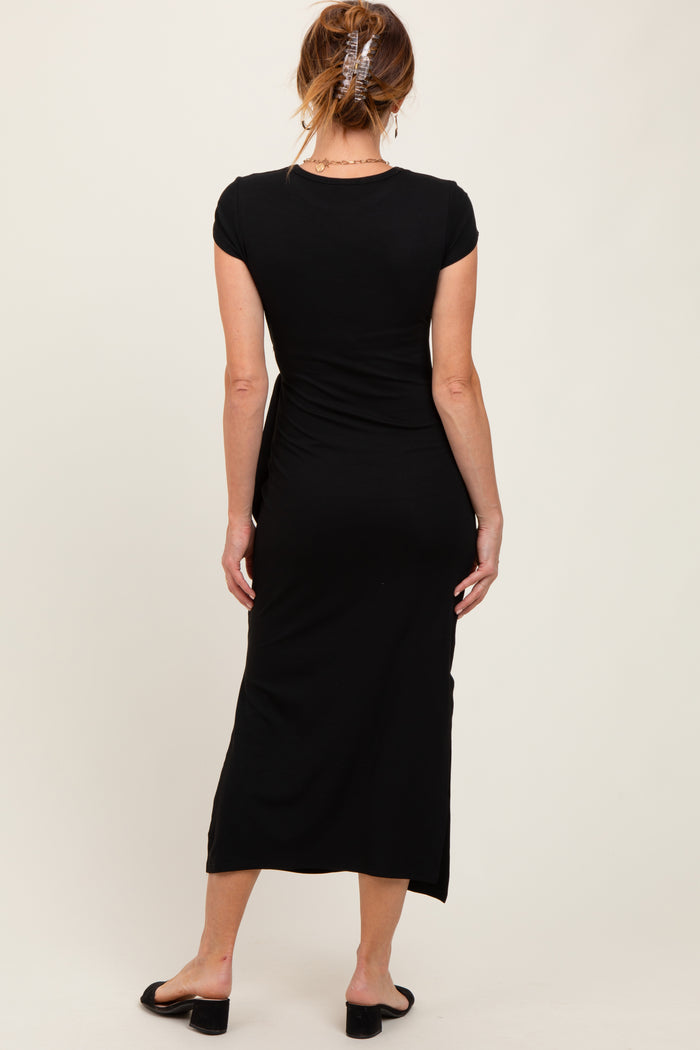 woman wearing a black cap sleeve maxi dress, showing a fitted silhouette and a side slit, viewed from the back