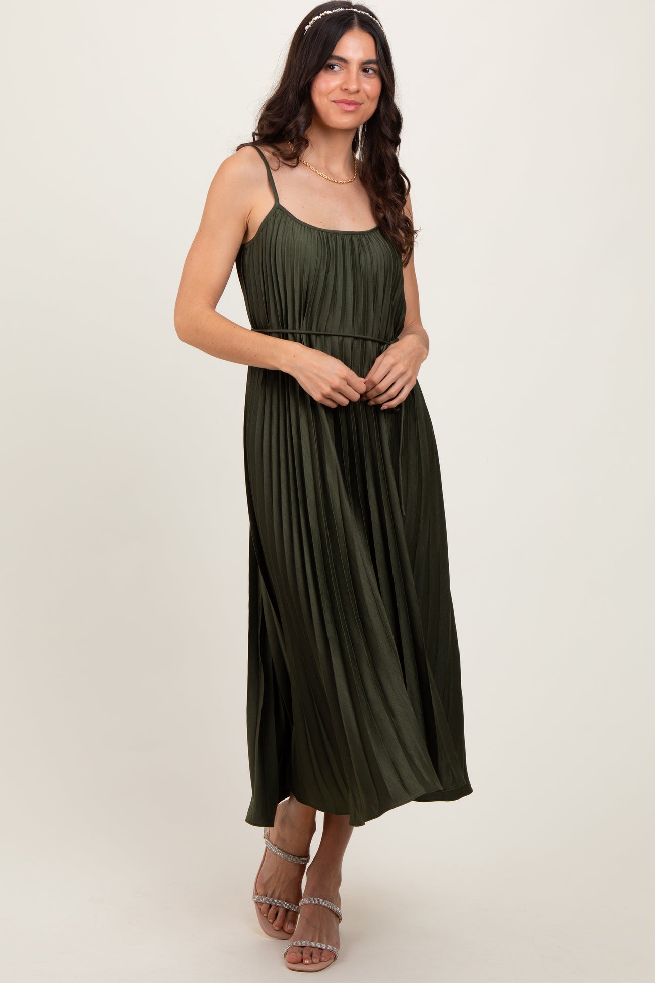 woman wearing a dark olive green pleated maxi dress with spaghetti straps and a flowing silhouette