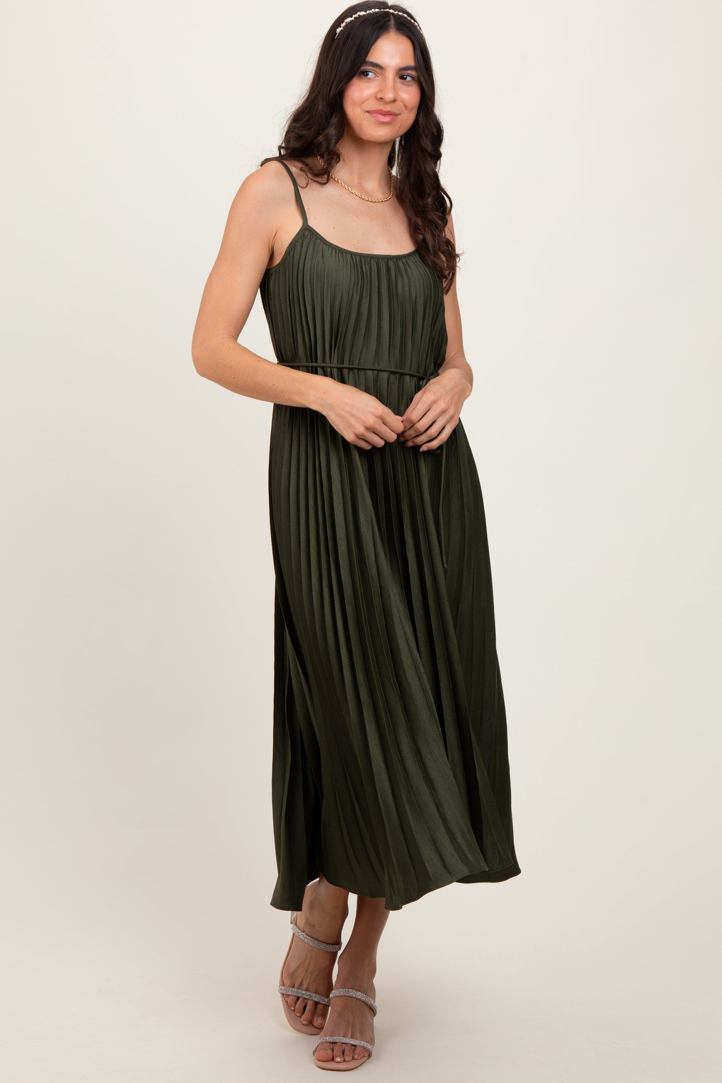 woman wearing a dark olive green pleated maxi dress with spaghetti straps and a flowing silhouette