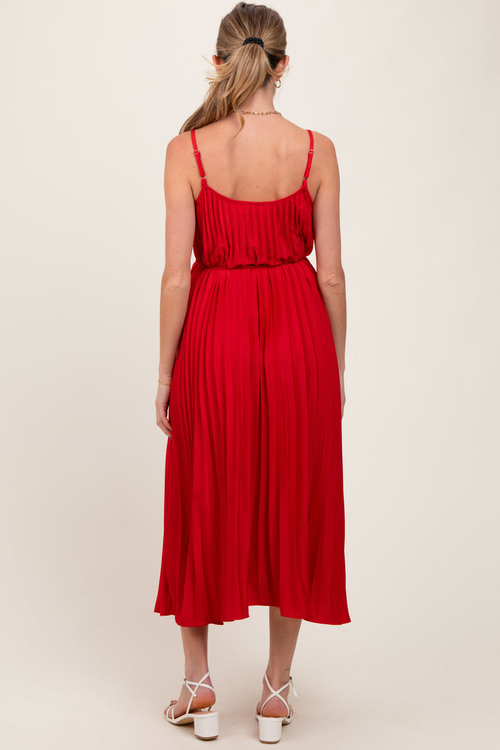 woman wearing a red pleated maternity dress with adjustable straps, showing the back view and a flowing silhouette