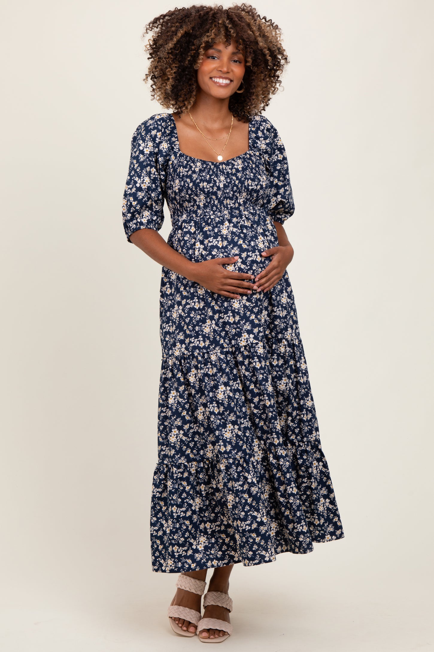 woman wearing a navy blue floral maternity maxi dress with puff sleeves and holding her baby bump