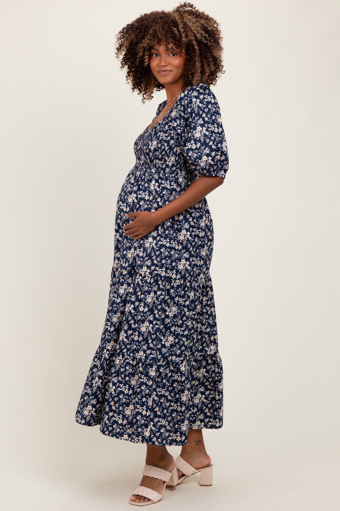 woman wearing a navy blue floral maternity dress with short sleeves and a flowy skirt, showing her baby bump