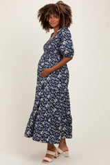 woman wearing a navy blue floral maternity dress with short sleeves and a flowy skirt, showing her baby bump