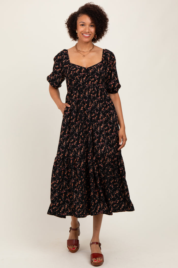 woman wearing a black floral maxi dress with puff sleeves and a square neckline, standing and smiling