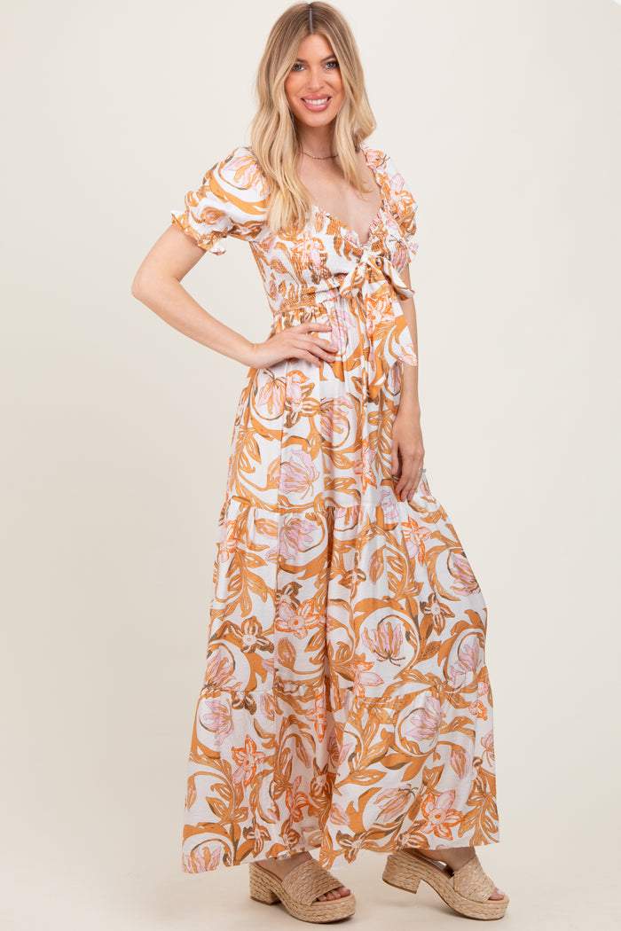 woman wearing a white maxi dress with orange floral print and puff sleeves, styled with beige espadrille wedges