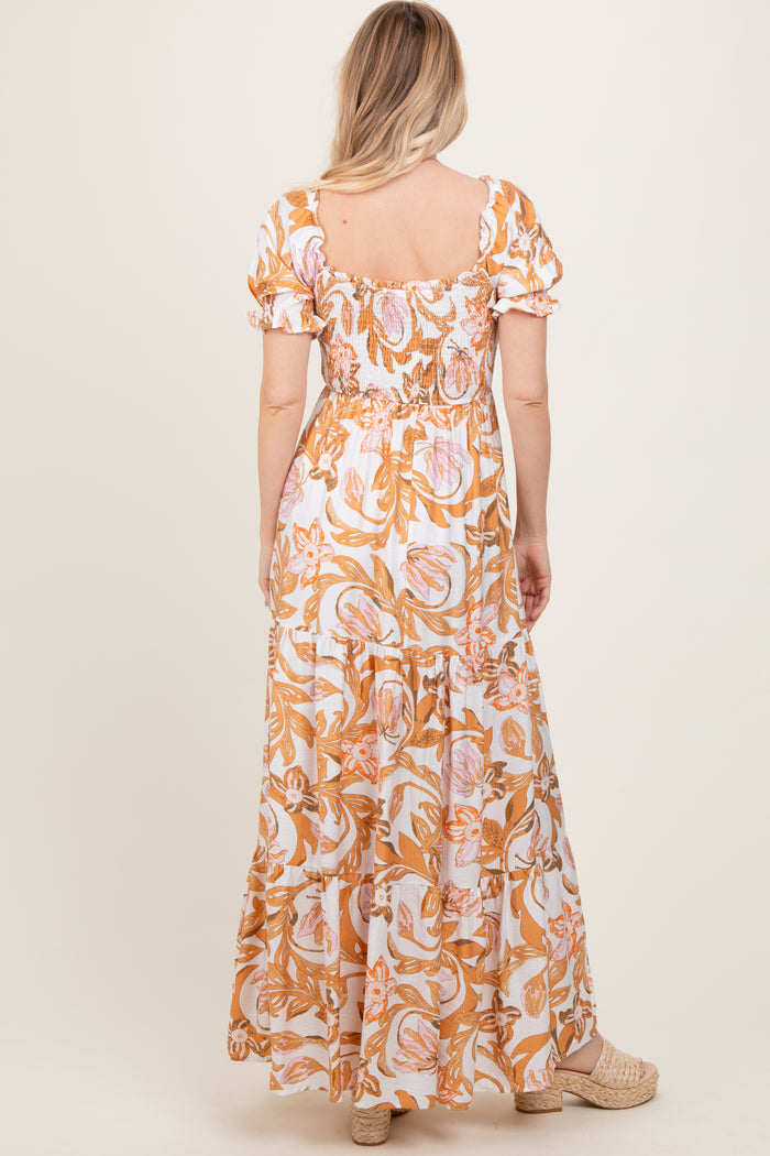 woman wearing a tan and pink floral print maxi dress with short puff sleeves and a smocked bodice, viewed from the back