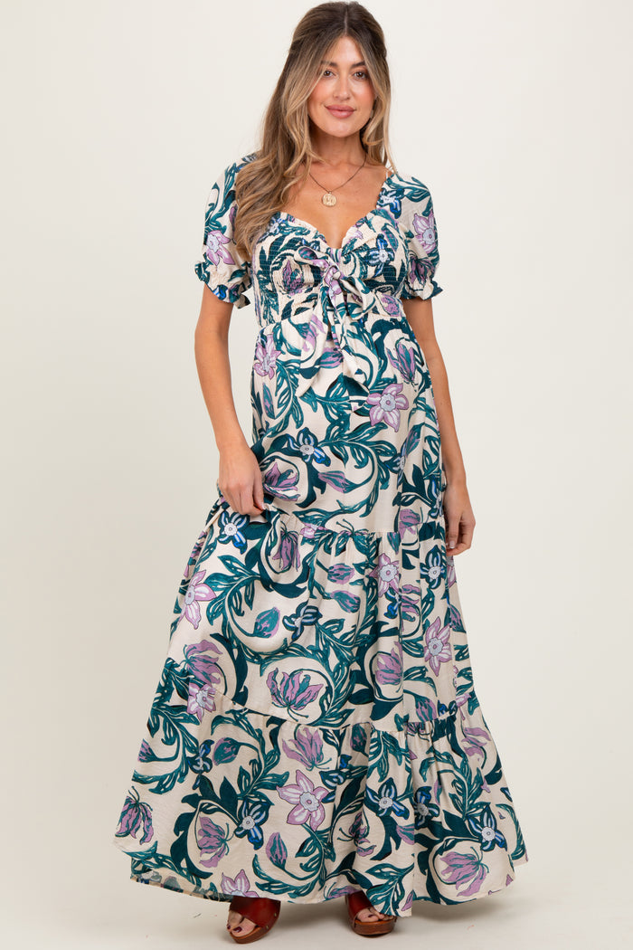 woman wearing a floral print maternity maxi dress with a tie detail and puff sleeves, showcasing her baby bump