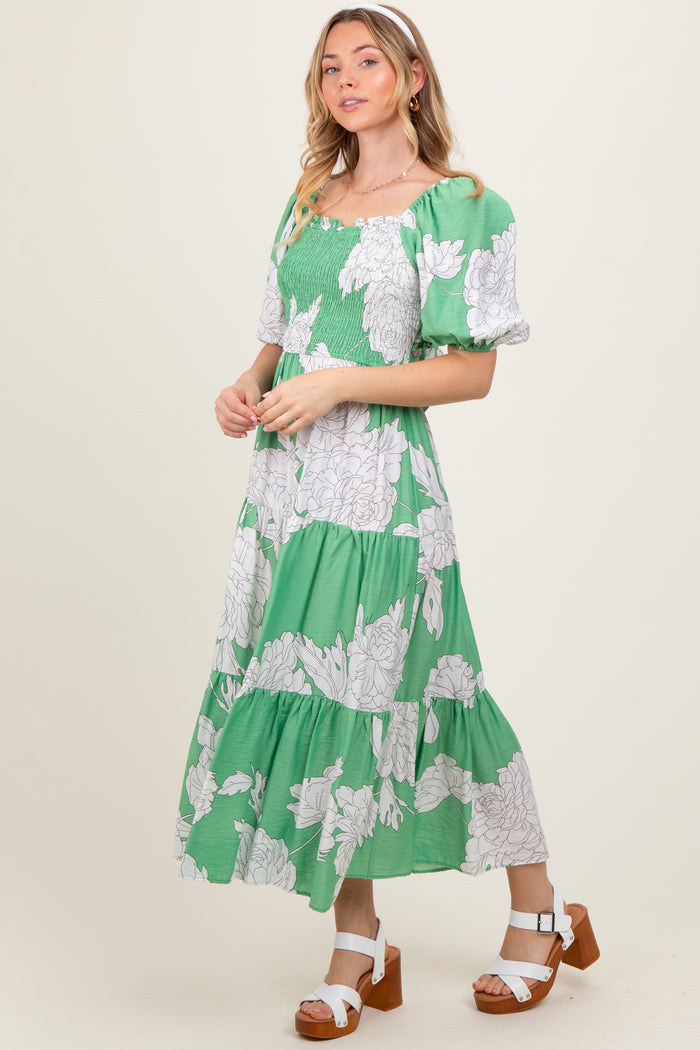 woman wearing a green floral maxi dress with puff sleeves and a tiered skirt