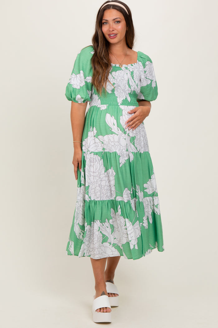 woman wearing a green floral maternity dress with puffed sleeves and a baby bump visible