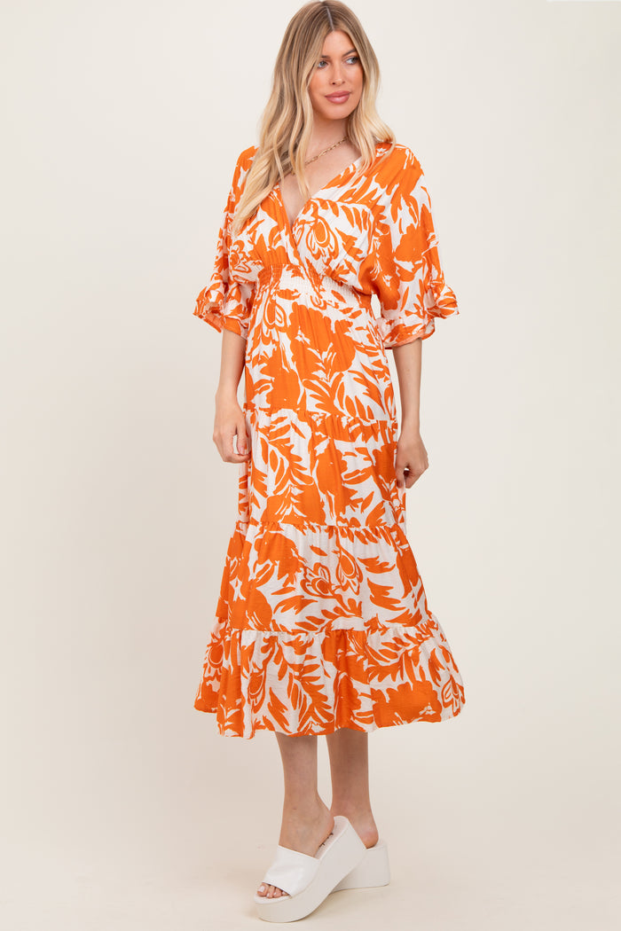 woman wearing an orange and white floral print maxi dress with ruffled sleeves and a flowing skirt